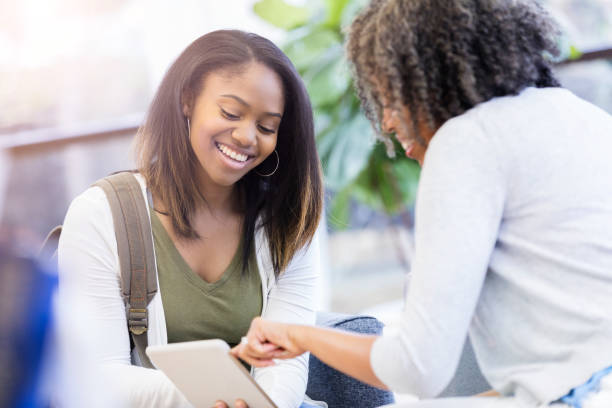 High school counselor visits with teenage girl Confident African American high school guidance counselor uses digital tablet to discuss education plans with female student. school counselor stock pictures, royalty-free photos & images