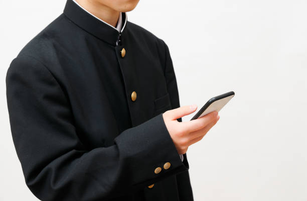 スマートフォンを使う高校生 - 制服 ストックフォトと画像