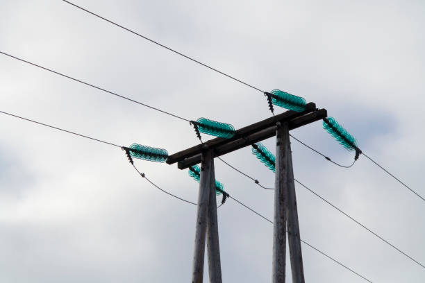 High voltage electrical cables on poles, with a backdrop of a cloudy sky. The lines are attached to the poles with glass insulation. The lines are running through the Icelandic highlands. stock photo