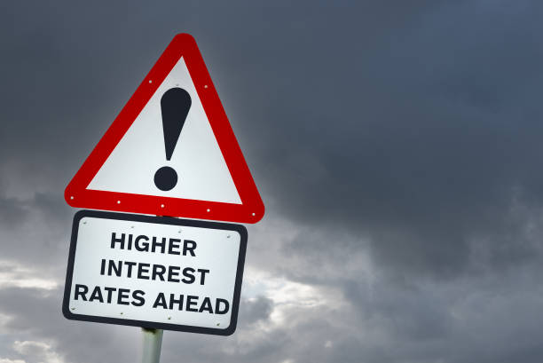 Higher interest rate ahead: conceptual warning road sign against cloudy sky stock photo