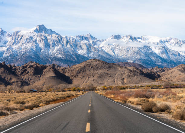 Highway heading toward Sierra Nevada mountains covered by snow.  California, USA stock photo