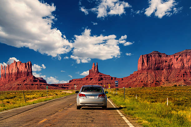 Highway in Monument Valley, Utah / Arizona, USA Monument Valley, United States - September 10, 2015: Highway in Monument Valley, Utah / Arizona, USA - Picture with road and cars driving towards the hills. Photo made during a road trip throughout the western states. mesa stock pictures, royalty-free photos & images