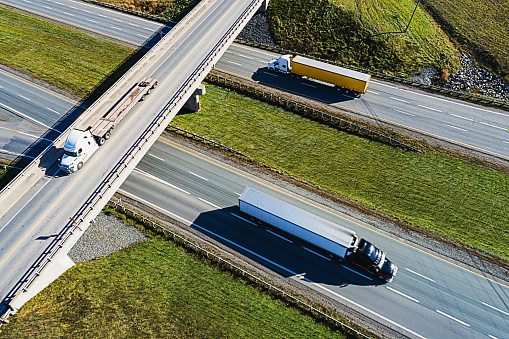 Aerial drone view of  three semi trucks on a multilane highway.