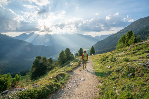Hiker male hiking down trail in beautiful nature environment in the Swiss alps Hiker male hiking down trail in beautiful nature environment in the Swiss alps graubunden canton stock pictures, royalty-free photos & images