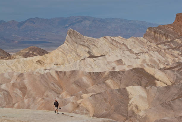 Hiker near Zabriskie Point Death Valley National Park, California, USA - April 02, 2018: A lone hiker is strolling with his camera in hand near Zabriskie Point. jeff goulden mojave desert stock pictures, royalty-free photos & images