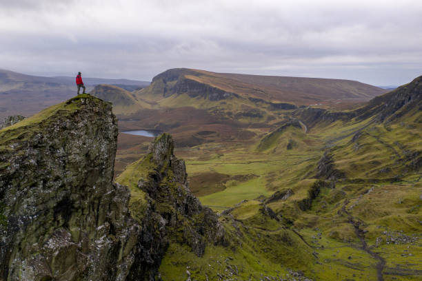 wandelaar staande op de bergtop in ruige vulkanische landschap rond de oude man van storr, isle of skye, schotland - isle of skye stockfoto's en -beelden