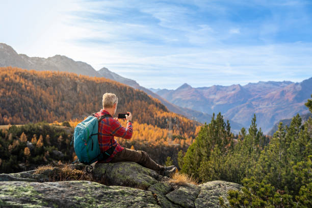 Hiker taking a photo with smartphone of the autumn valley stock photo