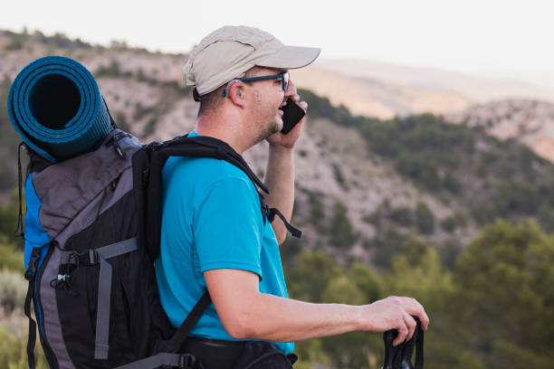 A hiker talking on his cell phone in the mountains stock photo