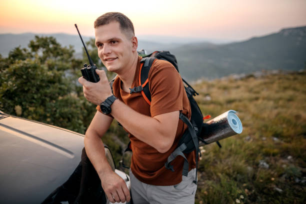 Hiker talking on radio while resting in mountains stock photo