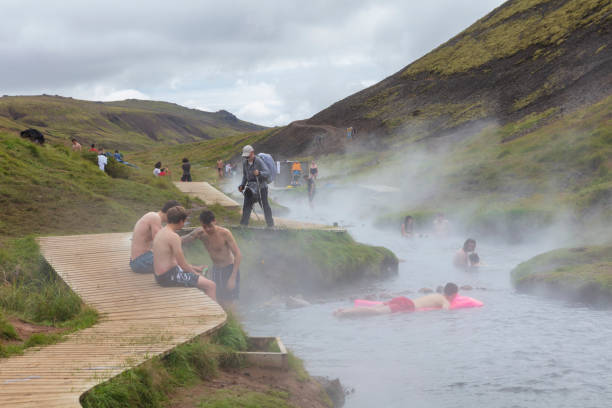 Hikers bathe in the  geothermal springs near Hringsja, loacated in southern Iceland during a cloudy day. stock photo