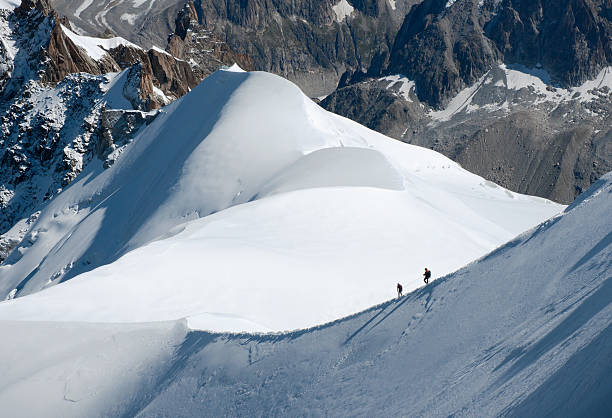 Hikers on a Narrow Glacier Ridge Near Mont Blanc stock photo