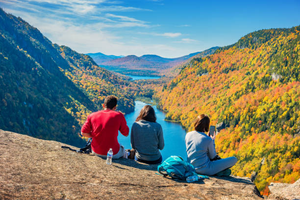 Hikers rest in the Adirondack Mountains New York State USA during Autumn Three hikers rest in the Adirondack Mountains New York State USA during Fall colors. adirondack state park stock pictures, royalty-free photos & images