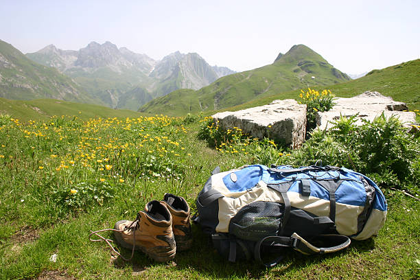 Hiking gear in a flowering mountain meadow  A back pack and walking boots laying in a meadow of yellow flowers in fron of a mountain scene above Lech in Austria. lech river stock pictures, royalty-free photos & images