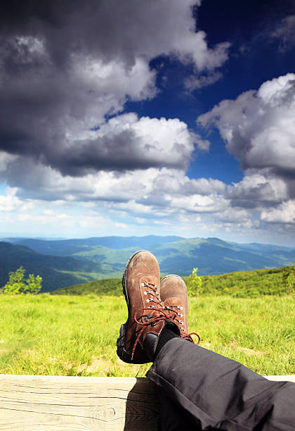Hiking shoes boots. Male hiker enjoying view relaxing looking at...