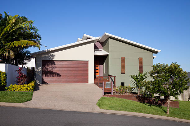 Hill side home front "Front of a new neat modern single story family home built on a hill side with landscaped gardens, green grass and blue sky for copy space. Click to see more..." bungalow stock pictures, royalty-free photos & images