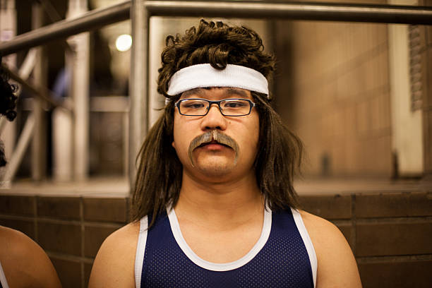 Hillbilly basketball player cosplay.  Halloween NYC 2014 New York City, NY, USA - October 31, 2014: Young Asian man dressed as a hillbilly basketball player, waits for the #6 train on Halloween night. mullet haircut stock pictures, royalty-free photos & images