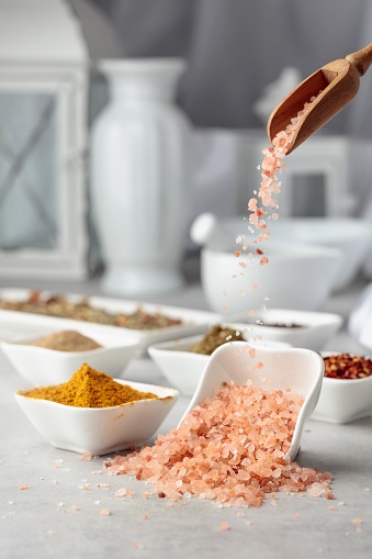 Himalayan pink salt and various spices on a kitchen table.