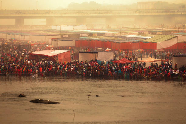 Hindu devotee celebrating Chhath Pooja festival during winter foggy day Delhi, India – November 13, 2018 - Hindu devotee praying to god and celebrating on occasion of Chhath Pooja festival. Large group of people gathered every festival at the edge of Yamuna river. Chhath is an ancient Hindu Vedic festival historically native to the Indian subcontinent, more specifically, the Indian states of Bihar, Jharkhand, and Uttar Pradesh as well as the Madhesh region of Nepal. chhath stock pictures, royalty-free photos & images