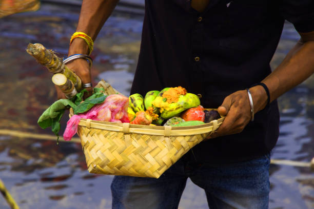 Hindu devotee offer prasad ,fruits,vegetables and other items , to pray sun God,at a lake,during Chhath Puja Hindu devotee offer prasad ,fruits,vegetables and other items , to pray sun God,at a lake,during Chhath Puja chhath stock pictures, royalty-free photos & images