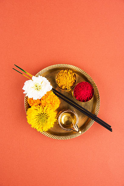 hindu puja thali, indian culture Beautifully Decorated Pooja Thali for diwali celebration to worship, huldi or turmeric powder and kumkum, flowers, scented sticks in brass plate on orange background, hindu puja thali hinduism photos stock pictures, royalty-free photos & images