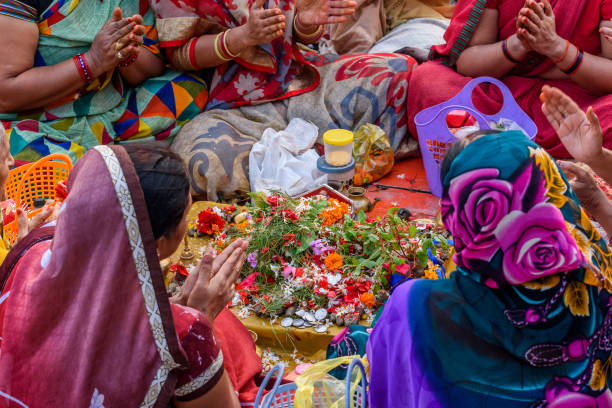 Hindu women October 14,2017. Varanasi,India. Hindu women  praying mantras as part of a ritual ceremony at the Ganges river ghat Varanasi, India. chhath stock pictures, royalty-free photos & images