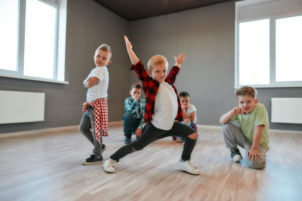 hip-hop-stil. gruppe von niedlichen kleinen jungs in modischen kleidung tanzen und posieren im studio. choreographie-kurs. kinder und sport. volle länge - tanzende kinder stock-fotos und bilder