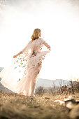 Young woman in a romantic dress enjoying in the field,rear view