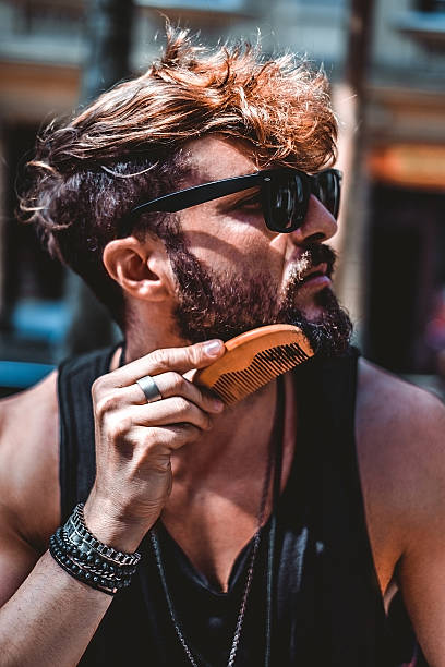 Hipster combing beard on a sunny day stock photo