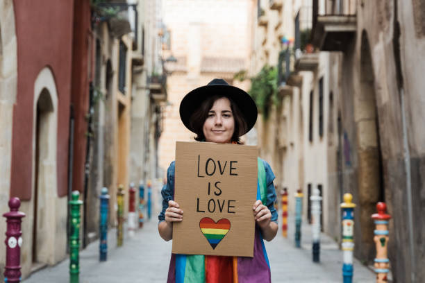 Hipster gay woman holding lgbt banner with rainbow flag - Focus on lesbian girl face stock photo