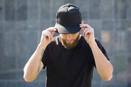 Hipster handsome male model with beard wearing black blank  baseball cap  with space for your logo