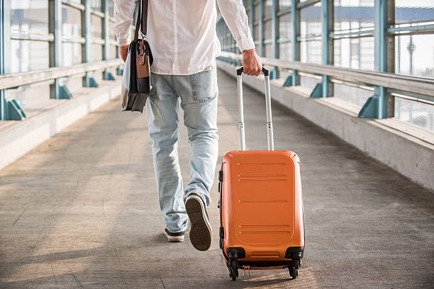 Hipster Male Walking on Bridge with Suitcase stock photo