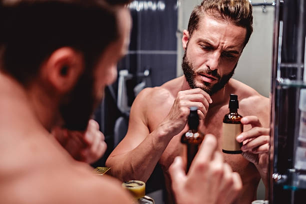 Hipster man holding bottle in the bathroom Hipster shirtless man holding bottle in the bathroom grooming product stock pictures, royalty-free photos & images