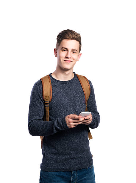 Hipster man holding smartphone, talking. Isolated. Hipster teenage boy in eyeglasses, jeans and striped sweater, holding smart phone, making phone call. Young man. Studio shot on white background, isolated. adolescence stock pictures, royalty-free photos & images