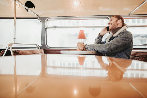 jeune mâle de conversation de hipster par le téléphone dans le bus de café - smartphone car photos et images de collection