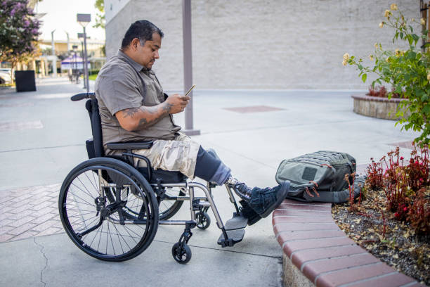 Hispanic American Veteran College Student Using Smartphone A young Hispanic American Veteran college student going to class. He is a double amputee. fat man looks at the phone stock pictures, royalty-free photos & images
