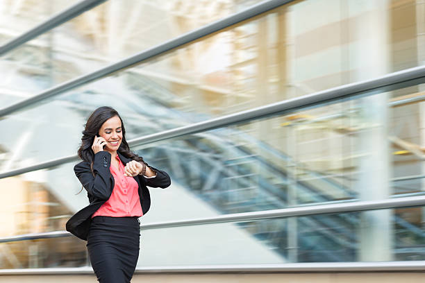 hispanic business women on phone walking in a rush - fast business stockfoto's en -beelden