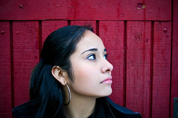Hispanic Gaze Young Hispanic girl pausing to think in front of red door.VIEW SERIES: Dreary Beauty mexican teenage girls stock pictures, royalty-free photos & images