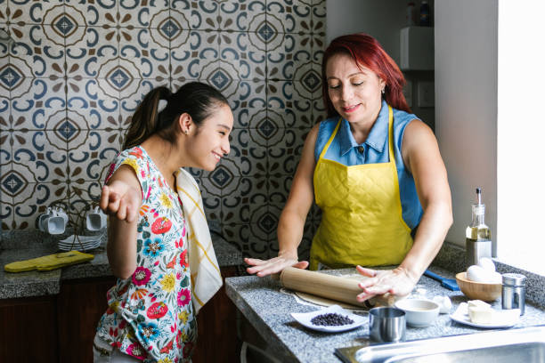 Hispanic girl with cerebral palsy and her mother cooking at home, in disability concept in Latin America Hispanic girl with cerebral palsy and her mother cooking at home, in disability concept in Latin America mexican teenage girls stock pictures, royalty-free photos & images