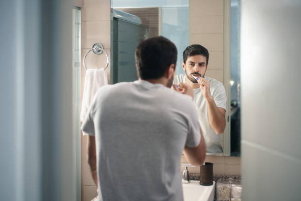 Hispanic Man Brushing Teeth In Bathroom At Morning stock photo
