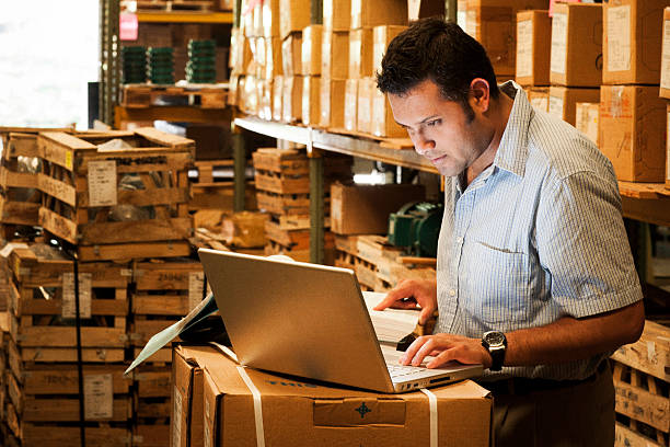 Hispanic Manager in Warehouse Hispanic manager working in warehouse going over inventory and shipping and receiving. cargo container photos stock pictures, royalty-free photos & images