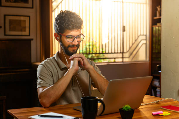 Hispanic model giving a slight smile during online conversation with distant family members. Concept working at home stock photo