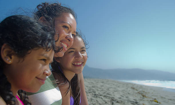Hispanic Mom With Her Daughters On The Beach stock photo
