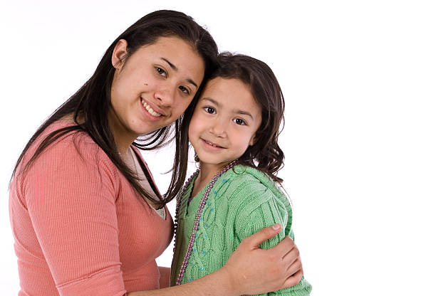 Hispanic sisters hugging stock photo