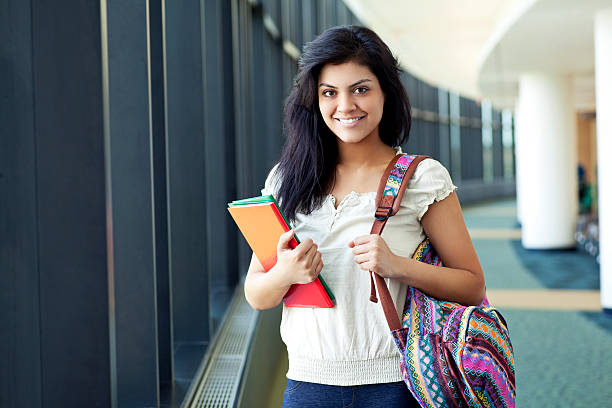 Hispanic student smiling Pretty hispanic young student in front of a campus or school wearing a book bag and carrying a notebook. cute puerto rican girls stock pictures, royalty-free photos & images