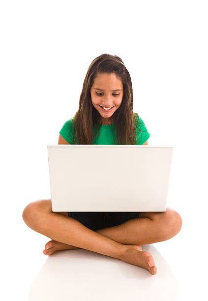 Hispanic teenager sitting cross legged working on laptop stock photo