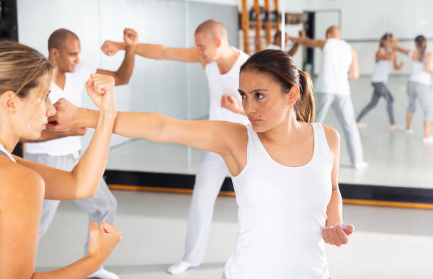 Hispanic woman practicing self defense moves with female partner stock photo