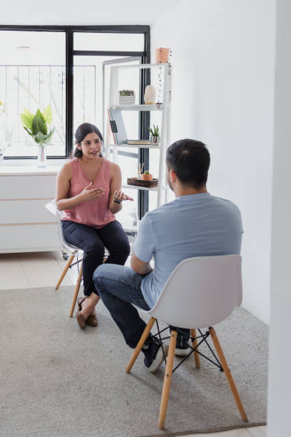 Hispanic young woman psychologist with male patient telling about mental problems while doctor is listening and making notes. Psychotherapy concept in Mexico Latin America stock photo