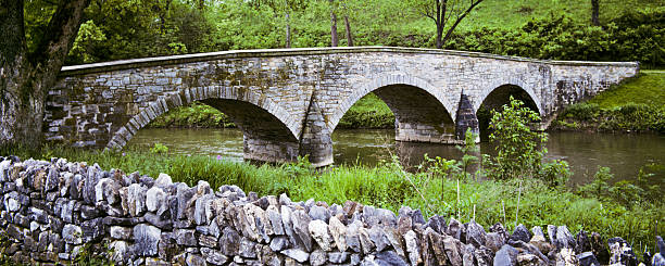 Historic Burnside Bridge and Stone Wall The Burnside Bridge over Antietam Creek played a key role in the September 1862 Battle of Antietam during the American Civil War. Around 500 Confederate soldiers from Georgia held off repeated attempts by the Union Army under Major General Ambrose E. Burnside, to take the bridge. The bridge is in the Antietam National Battlefield near Sharpsburg, Maryland, USA. jeff goulden panoramic stock pictures, royalty-free photos & images