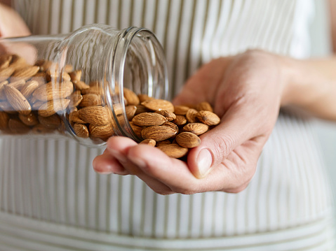 Close up shot of a woman taking almonds from a glass jar