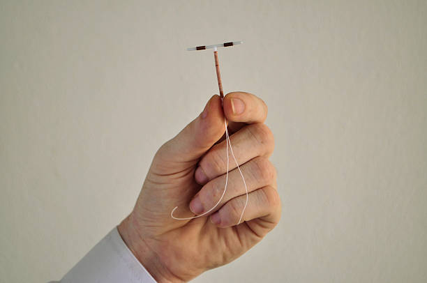 Holding an IUD birth control device in fingers Holding an IUD birth control copper coil device between fingers, used for contraception iud stock pictures, royalty-free photos & images